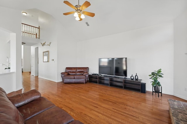 living room featuring visible vents, high vaulted ceiling, a ceiling fan, wood finished floors, and baseboards