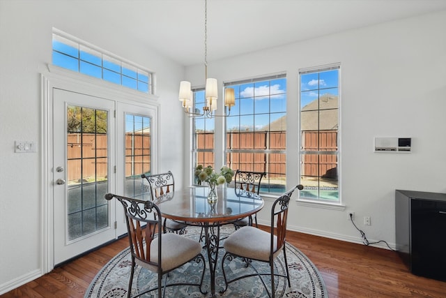 dining room with a notable chandelier, dark wood-type flooring, and baseboards