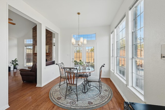 dining room featuring ceiling fan with notable chandelier, wood finished floors, and baseboards