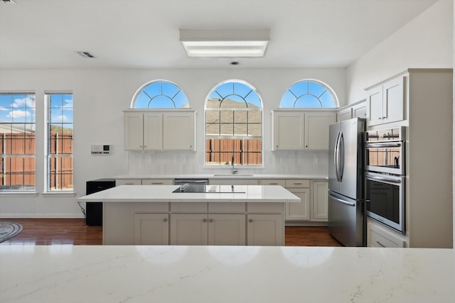 kitchen with visible vents, dark wood-style flooring, a sink, appliances with stainless steel finishes, and backsplash