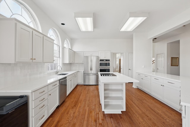 kitchen with open shelves, a sink, tasteful backsplash, stainless steel appliances, and light countertops