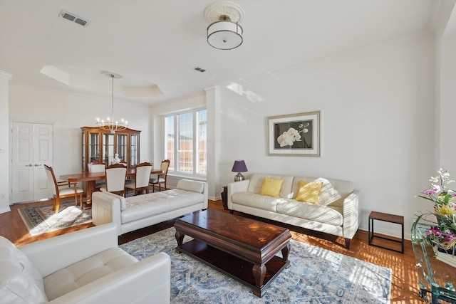 living area with visible vents, a raised ceiling, baseboards, and wood finished floors