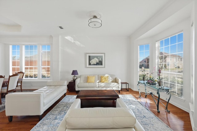 living room featuring visible vents, baseboards, and wood finished floors