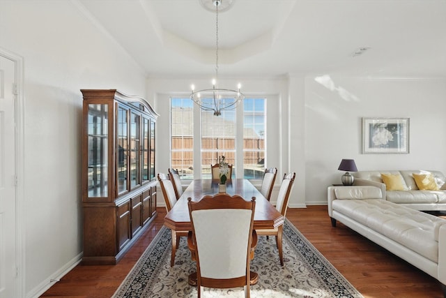 dining room with crown molding, baseboards, dark wood finished floors, a chandelier, and a tray ceiling