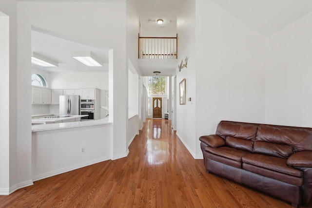 interior space featuring plenty of natural light, a high ceiling, baseboards, and wood finished floors