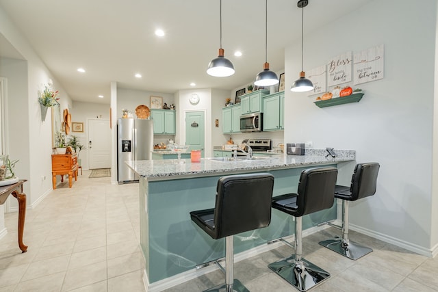 kitchen featuring green cabinetry, a breakfast bar, a peninsula, stainless steel appliances, and a sink