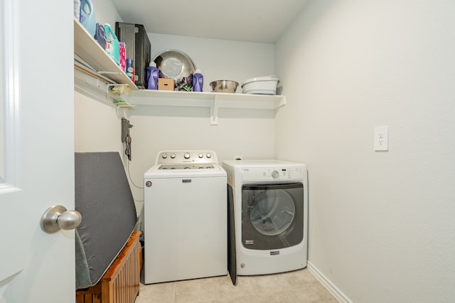 laundry area featuring washing machine and clothes dryer, laundry area, baseboards, and light tile patterned floors