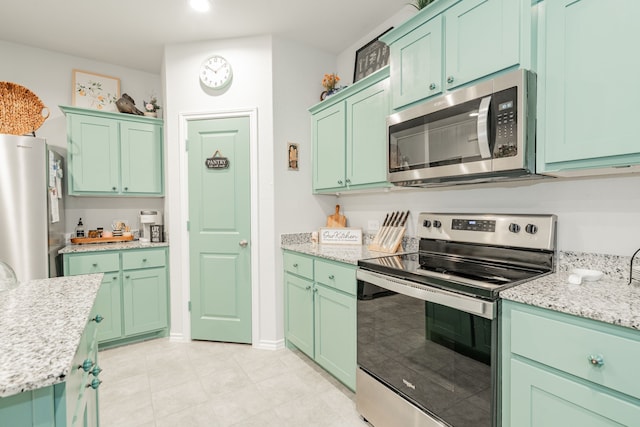 kitchen featuring green cabinets, light stone countertops, and stainless steel appliances