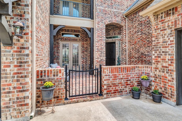 view of exterior entry with brick siding and a gate