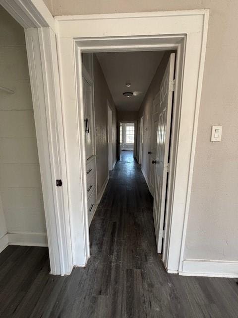 corridor featuring baseboards and dark wood-style flooring