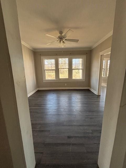 empty room featuring baseboards, dark wood-style flooring, and crown molding