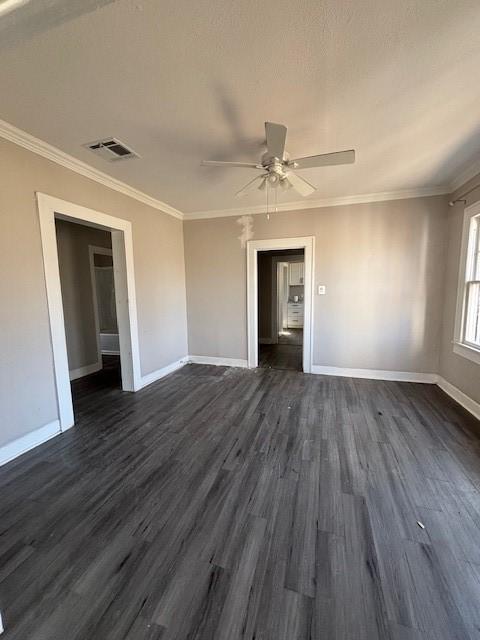 unfurnished room featuring visible vents, dark wood-style flooring, baseboards, and ornamental molding