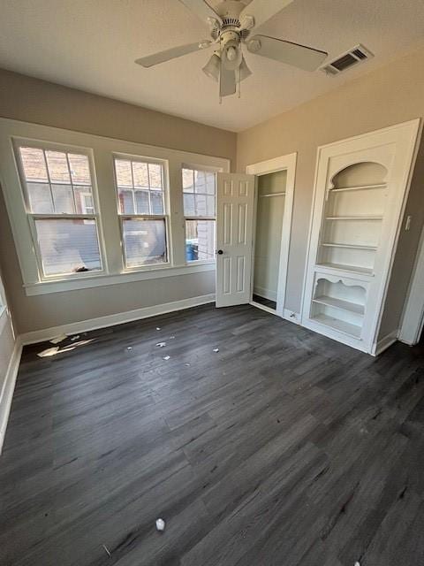 unfurnished bedroom with visible vents, a ceiling fan, dark wood-type flooring, and baseboards