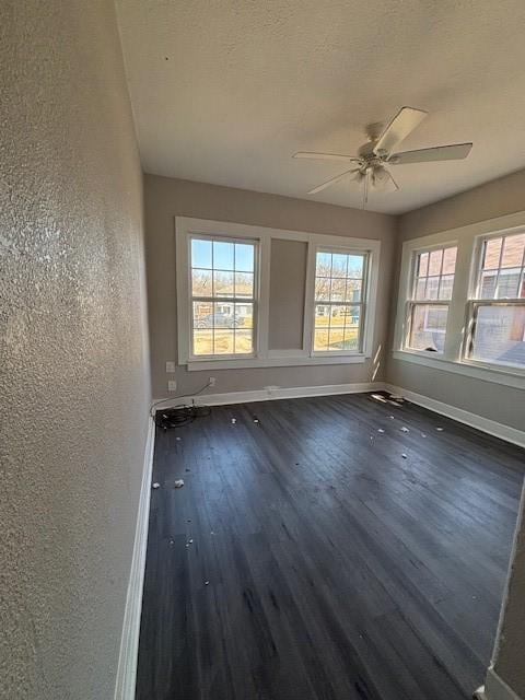 empty room with baseboards, ceiling fan, dark wood-style flooring, and a textured wall