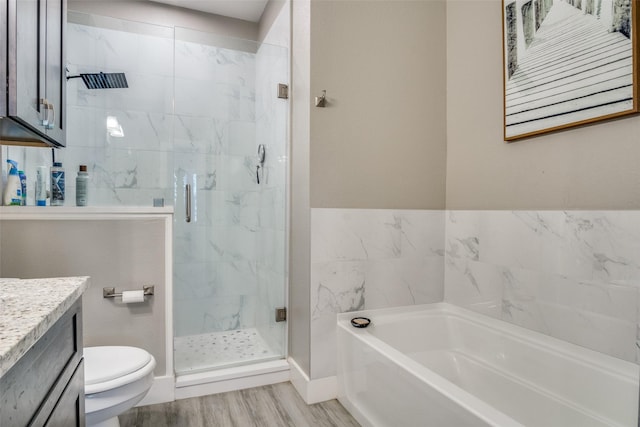 bathroom with toilet, wood finished floors, a shower stall, a bath, and vanity