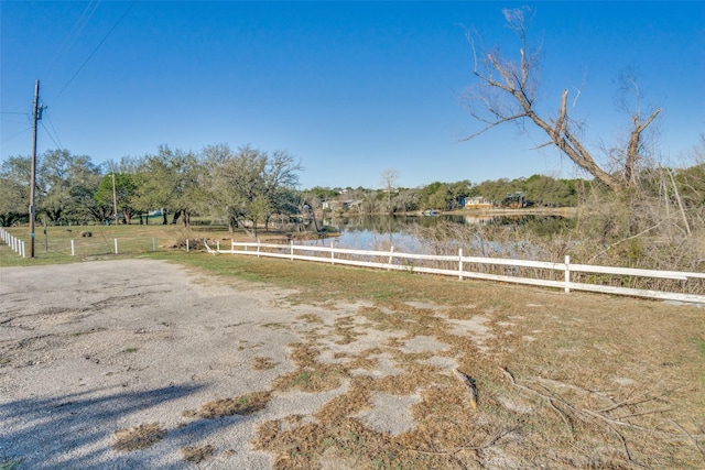 view of yard with a rural view, a water view, and fence