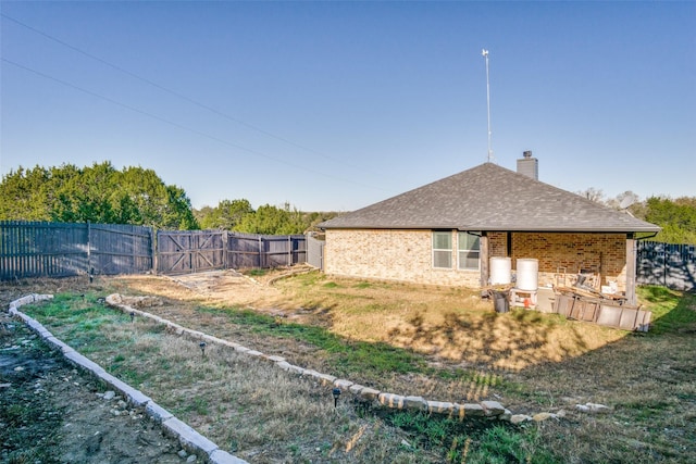 view of home's exterior with a chimney, fence, brick siding, and a shingled roof