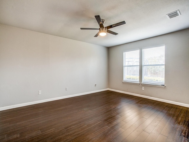 empty room featuring visible vents, dark wood-type flooring, a textured ceiling, baseboards, and ceiling fan