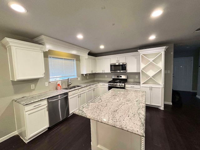 kitchen with dark wood finished floors, a sink, stainless steel appliances, white cabinets, and a center island