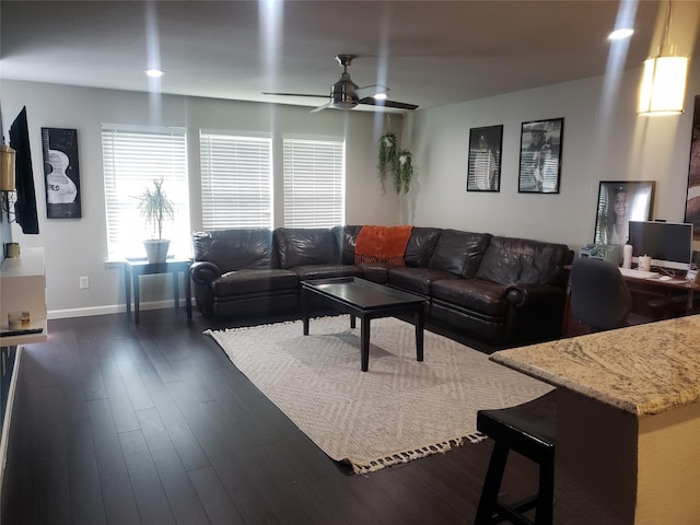 living area with baseboards, dark wood-type flooring, and ceiling fan