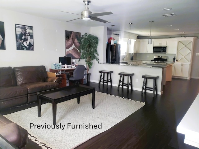 living room with ceiling fan, visible vents, baseboards, and dark wood-style floors