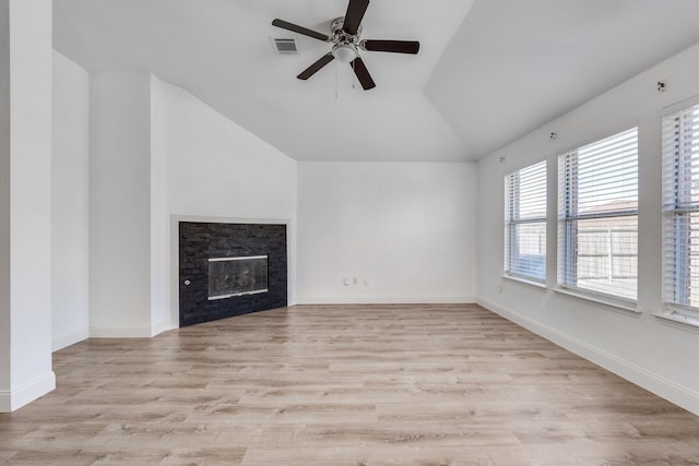 unfurnished living room featuring baseboards, visible vents, lofted ceiling, a glass covered fireplace, and light wood-type flooring