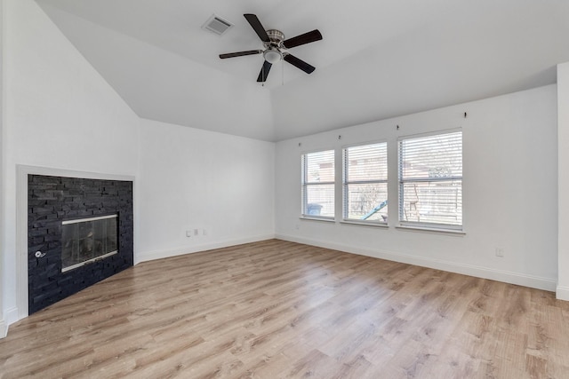 unfurnished living room with visible vents, light wood finished floors, baseboards, lofted ceiling, and a fireplace