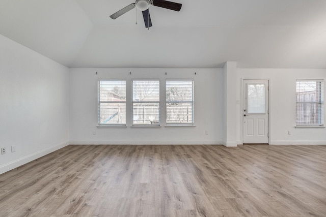 unfurnished living room with vaulted ceiling, wood finished floors, baseboards, and a wealth of natural light