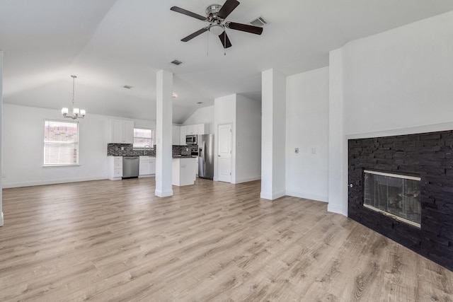 unfurnished living room with visible vents, ceiling fan with notable chandelier, a fireplace, and vaulted ceiling