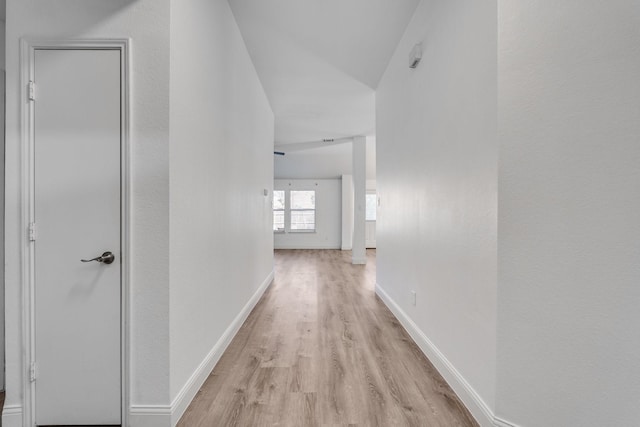 hall with baseboards and light wood-style floors