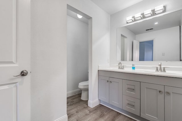 full bathroom featuring visible vents, toilet, wood finished floors, and a sink