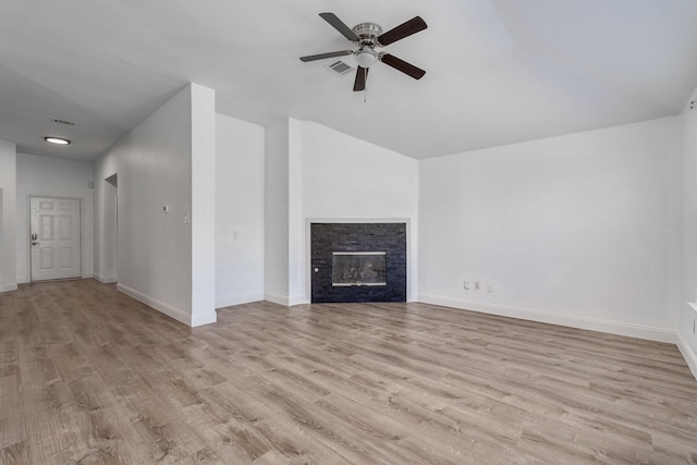 unfurnished living room with a stone fireplace, baseboards, visible vents, and wood finished floors