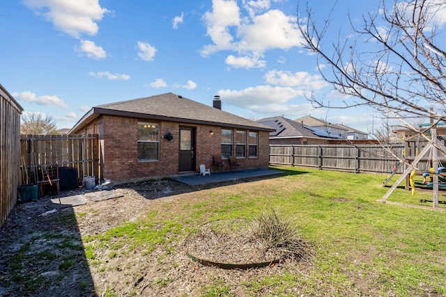 rear view of house with a patio, a fenced backyard, a playground, a yard, and brick siding