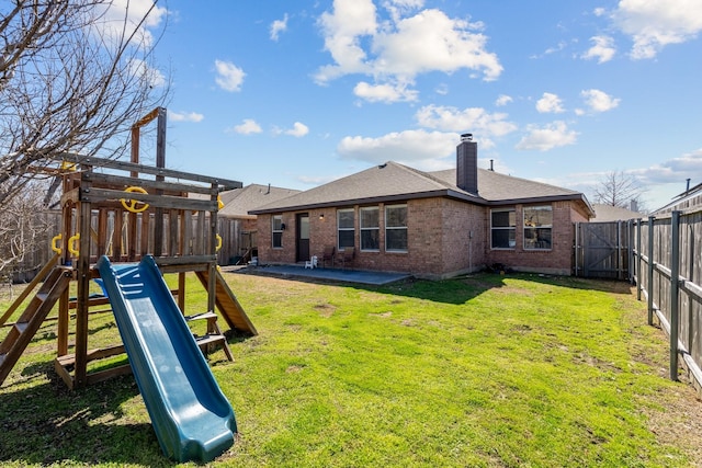 exterior space with brick siding, a playground, a lawn, a chimney, and a fenced backyard