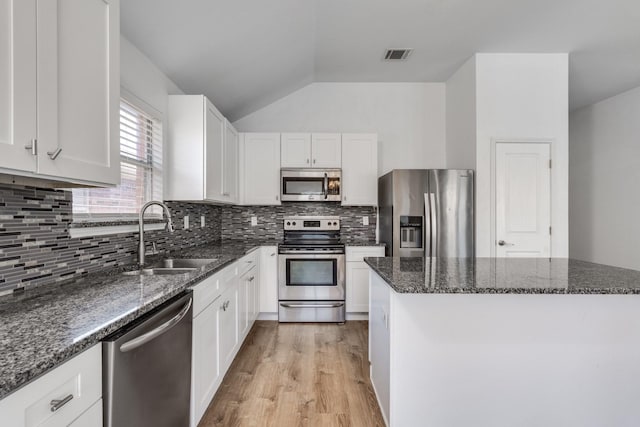 kitchen featuring visible vents, a sink, white cabinetry, stainless steel appliances, and dark stone counters