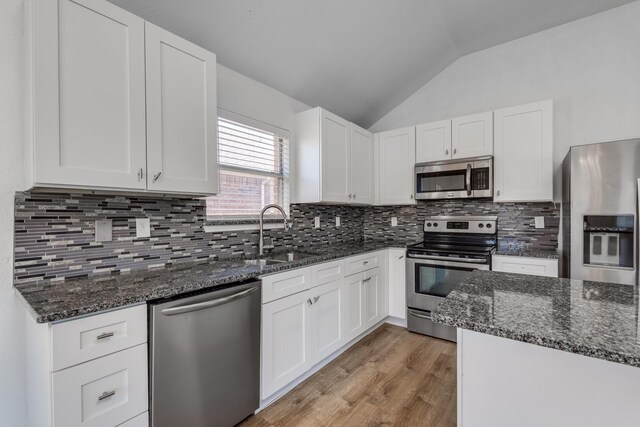 kitchen featuring a sink, stainless steel appliances, white cabinetry, and vaulted ceiling