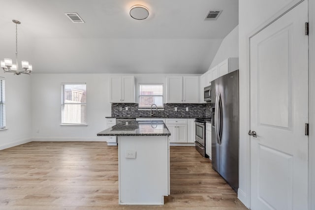 kitchen featuring visible vents, a kitchen island, stainless steel appliances, white cabinets, and backsplash