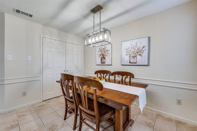 dining room with light tile patterned floors, visible vents, baseboards, and a textured ceiling