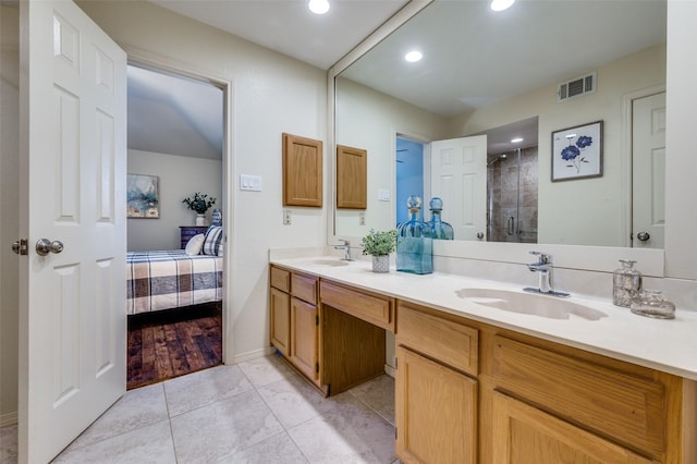 ensuite bathroom with double vanity, visible vents, a shower stall, and a sink