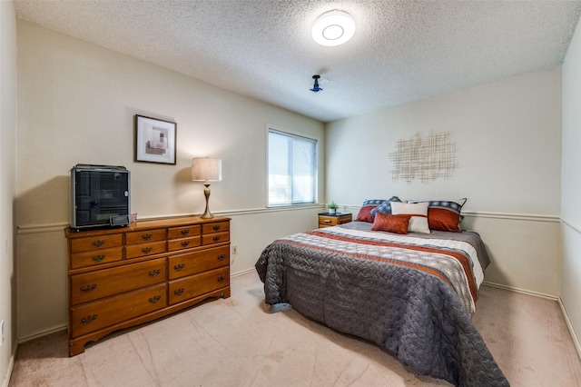 bedroom with light colored carpet, a textured ceiling, and baseboards