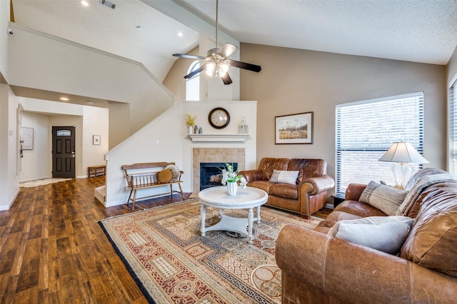 living area with baseboards, a tile fireplace, dark wood-style floors, high vaulted ceiling, and a ceiling fan