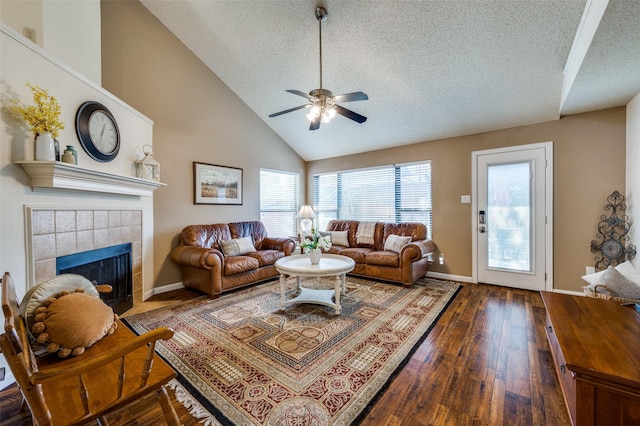 living area with a tiled fireplace, hardwood / wood-style flooring, a textured ceiling, and ceiling fan