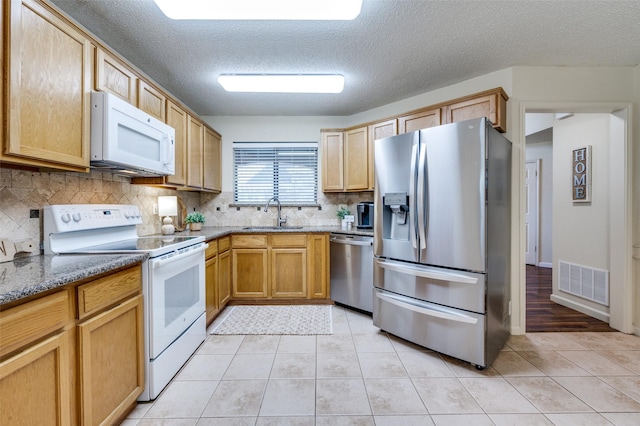 kitchen featuring visible vents, light tile patterned flooring, stone countertops, stainless steel appliances, and a sink