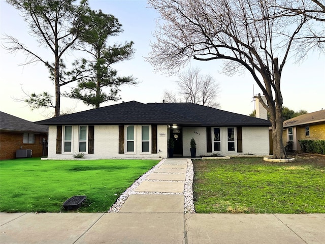 ranch-style house featuring brick siding, central AC, a front yard, and roof with shingles