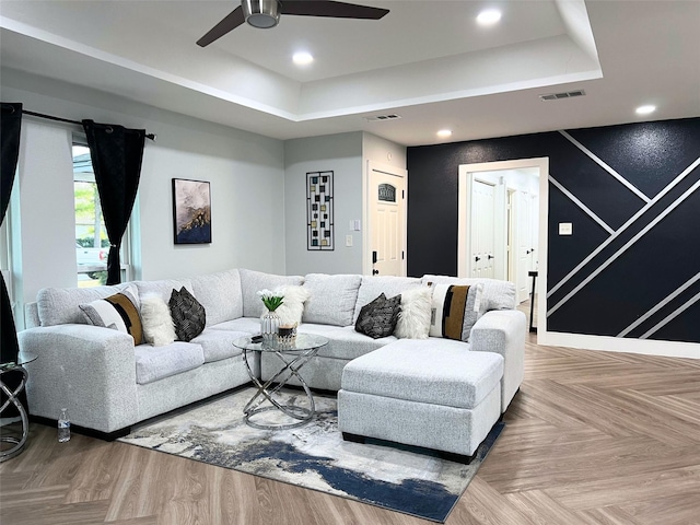 living area featuring recessed lighting, visible vents, and a raised ceiling