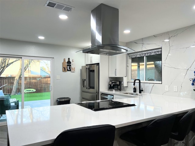 kitchen with visible vents, high end fridge, island exhaust hood, a sink, and light countertops