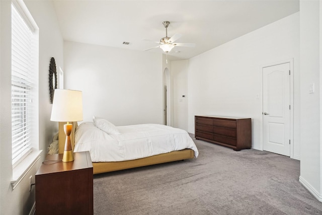 bedroom with visible vents, a ceiling fan, arched walkways, carpet flooring, and baseboards