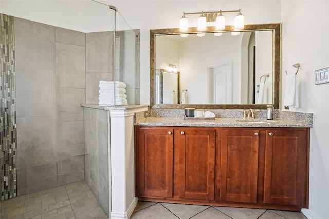 full bath featuring tile patterned floors, tiled shower, and vanity