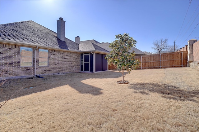 back of property featuring fence, brick siding, and a chimney