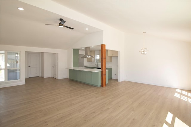 unfurnished living room with plenty of natural light, ceiling fan with notable chandelier, light wood-style flooring, and vaulted ceiling